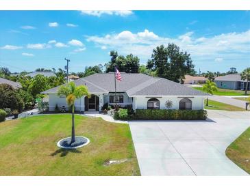 Aerial view of a single-Gathering home with a large driveway and landscaped yard at 254 Orlando Blvd, Port Charlotte, FL 33954