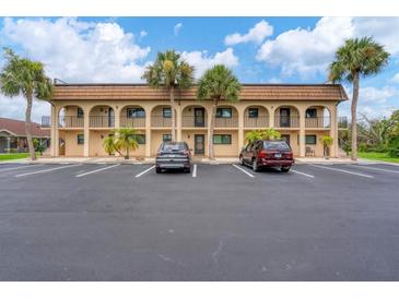 Building exterior featuring Spanish-style architecture and ample parking at 235 Rotonda Blvd W # C203, Rotonda West, FL 33947