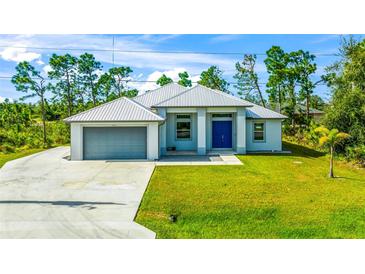 Single-story house with metal roof, attached garage, and a blue door at 9239 Harvester St, Port Charlotte, FL 33981