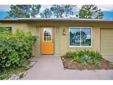 Tan house with an orange door and landscaping at 6517 Kenwood Dr, North Port, FL 34287