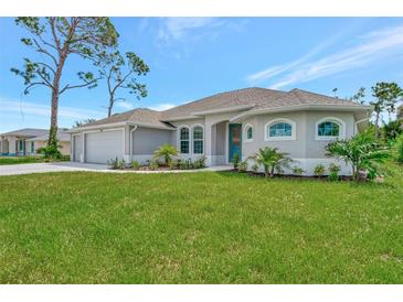 Single-story home with attached garage, manicured lawn, and palm trees at 261 Broadmoor Ln, Rotonda West, FL 33947