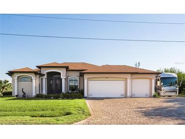 Charming single-story home with a well-manicured lawn and a three-car garage on a brick driveway at 15964 Viscount Cir, Port Charlotte, FL 33981
