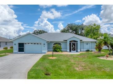 Single story home with light blue exterior, two-car garage, and landscaped lawn at 64 Long Meadow Ln, Rotonda West, FL 33947
