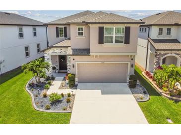 Charming two-story home with a manicured lawn, stone accents, and a spacious two-car garage at 7537 Pool Compass Loop, Wesley Chapel, FL 33545