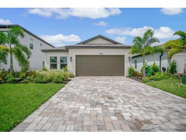 Single-story home with a brown garage door, landscaping, and a brick paver driveway at 1352 Sunset Preserve Way, Port Charlotte, FL 33953