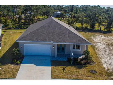 Aerial view of a single-story home with a two-car garage, well-manicured lawn, and mature trees at 721 Redbud Ct, Englewood, FL 34223