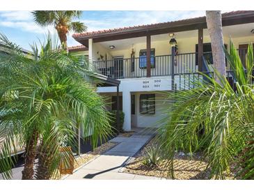 Exterior view of condo building with walkway and tropical landscaping at 504 Pine Hollow Cir # 504, Englewood, FL 34223