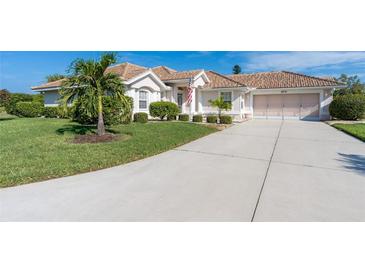 Single-story home with tile roof, landscaped yard, and driveway at 8216 Parkside Dr, Englewood, FL 34224