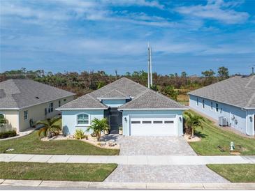 Charming single-story home with a manicured lawn, paver driveway, and an attached two-car garage at 552 Box Elder Ct, Englewood, FL 34223
