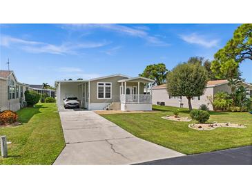 Tan mobile home with covered porch and driveway at 9085 Pinehaven Way, Englewood, FL 34224