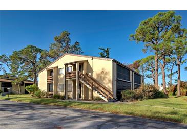 Two-story condo building with a wood staircase and screened-in patio at 19 Quails Run Blvd # 2, Englewood, FL 34223