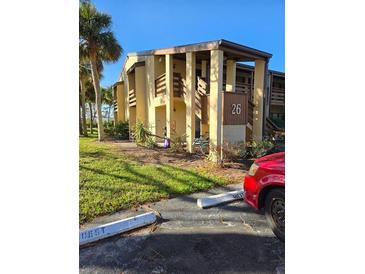 Exterior view of condo building with parking and landscaping at 26 Quails Run Blvd # 7, Englewood, FL 34223