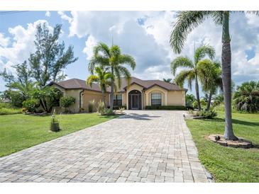 Beautiful one-story home with paver driveway, lush landscaping, and palm trees at 9381 St Paul Dr, Port Charlotte, FL 33981