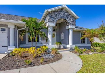 House exterior showcasing a gray house with stone accents, landscaping, and a walkway at 10083 Kansas City St, Port Charlotte, FL 33981