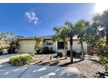 Single-story home with attached garage and tropical landscaping at 3075 Bay Oaks Cir, Englewood, FL 34223
