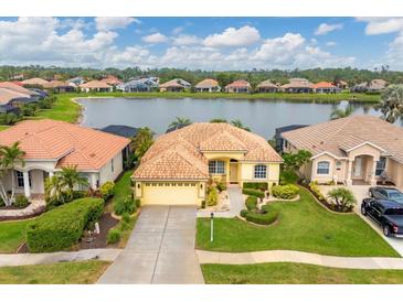 Aerial view of a yellow house with lake access in a Florida community at 1985 Coconut Palm Cir, North Port, FL 34288