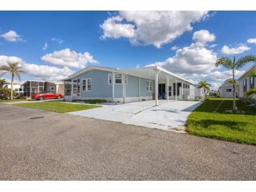 Light blue single-wide manufactured home with carport and landscaped yard at 749 Riverview Cir, North Port, FL 34287