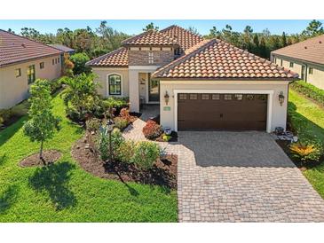Single-story home with tile roof, landscaping, and a paved driveway at 26790 Weiskopf Dr, Englewood, FL 34223