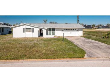 White single-story home with a two-car garage and grassy front yard at 11 Oakland Hills Rd, Rotonda West, FL 33947