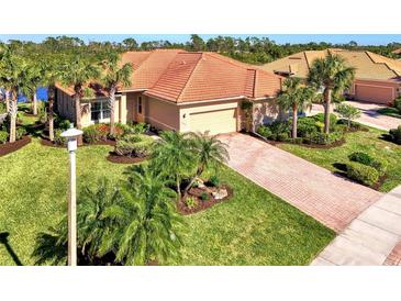 Aerial view of single-story house with tile roof, landscaping, and paved driveway at 13091 Creekside Ln, Port Charlotte, FL 33953