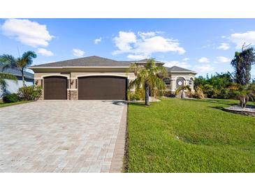 Charming single-story home with a three-car garage, manicured lawn, and paver driveway at 14010 San Domingo Blvd, Port Charlotte, FL 33981