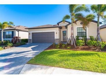 Single-story home with gray garage door, landscaping, and paver driveway at 19584 Fishhawk Trl, Venice, FL 34293