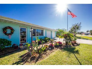 Cute bungalow with nicely landscaped front yard, featuring colorful flowers and lush greenery at 2495 Tenth St, Englewood, FL 34224