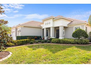 Single-story home with a tile roof, landscaped yard, and a neutral color scheme at 27429 Hole In One Pl, Englewood, FL 34223