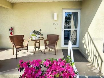 Inviting front porch with seating and blooming azaleas at 6600 Gasparilla Pines Blvd # 106, Englewood, FL 34224