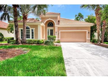 Tan one-story house with tile roof, two-car garage, and lush landscaping at 13123 Preserve Ct, Port Charlotte, FL 33953