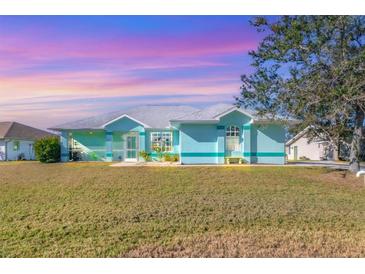 Charming one-story home with a light teal exterior, screened porch, and lush lawn at 2271 Paraiso Ct, Englewood, FL 34224