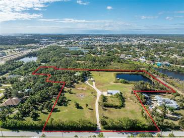 Aerial view of a large property with multiple buildings and a pond at 6341 Biggs St, Englewood, FL 34224