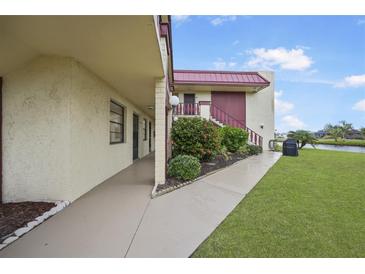 Exterior view of condo building, showing walkway, landscaping, and canal view at 66 Boundary Blvd # 282, Rotonda West, FL 33947