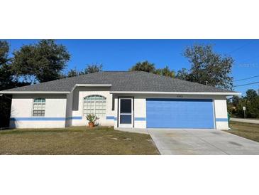 Single-story home with blue garage door and well-manicured lawn at 7472 Stetson Ln, Port Charlotte, FL 33981