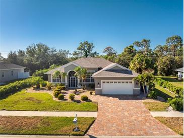 Charming single-story home with a paved driveway, attached garage, and lush landscaping at 112 Abercrombie Ave, Englewood, FL 34223