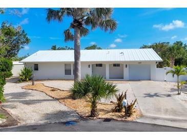 Charming single-story home with well-manicured landscaping and a white metal roof at 1493 Janet Pl, Englewood, FL 34223