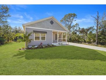 Cute gray house with a covered porch and well-manicured lawn at 19095 Willard Ave, Port Charlotte, FL 33954