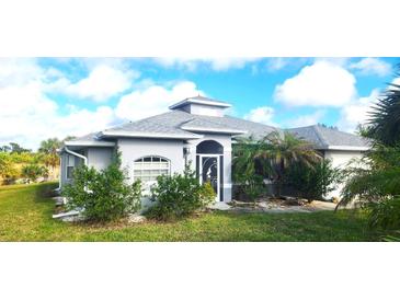 Gray one-story house with a landscaped yard, palm trees, and a screened-in entryway at 328 Baytree Dr, Rotonda West, FL 33947