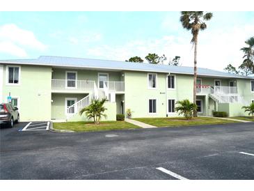 Light green two-story condo building with stairs, palm trees, and parking at 8100 Memory Ln # 207, Rotonda West, FL 33947