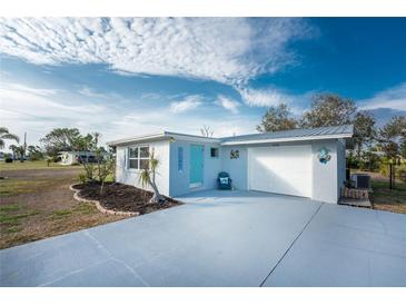 Charming single-story home featuring a well-maintained lawn, blue door, and an attached one-car garage at 850 E 2Nd St, Englewood, FL 34223