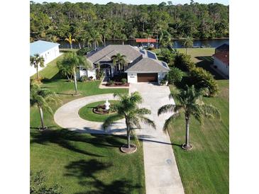 Aerial view of single-story home with circular driveway, landscaping, and waterfront access at 13307 Eisenhower Dr, Port Charlotte, FL 33953