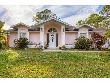 Pink one-story house with a white door, landscaping, and a green lawn at 5401 Kaspar St, Port Charlotte, FL 33981