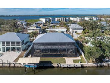 Rear exterior view of home with screened in lanai, boat dock, and waterfront at 9240 Pine Cove Dr, Englewood, FL 34224
