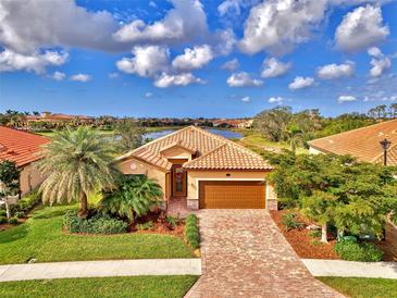 Charming single-Gathering home with a tile roof, lush landscaping, and a brick driveway with lake views at 20211 Granlago Dr, Venice, FL 34293