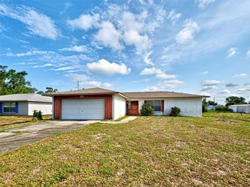 Single story home featuring an attached garage, red trim, and a lawn at 914 E 2Nd St, Englewood, FL 34223