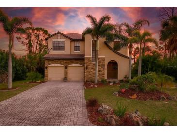 Inviting two-story home with a two-car garage, lush landscaping, and charming curb appeal highlighted by tropical palm trees at 117 Cable Dr, Rotonda West, FL 33947