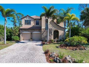 Inviting two-story home featuring a stone facade, paver driveway, and lush tropical landscaping at 117 Cable Dr, Rotonda West, FL 33947