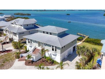 Coastal home with a metal roof and lush landscaping overlooking the water at 7180 Brittany Cir, Englewood, FL 34224