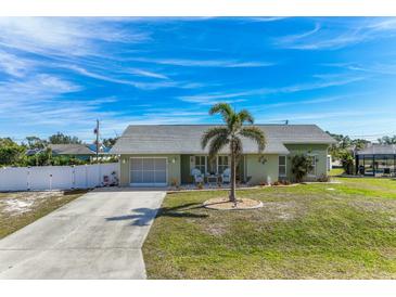 Charming single-story home features a well-manicured lawn, palm tree, and an inviting front porch seating area at 7586 Sea Mist Dr, Port Charlotte, FL 33981