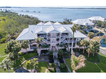 Stunning waterfront home with a white metal roof, lush landscaping, and multiple balconies overlooking the water at 11000 Placida Rd # 301, Placida, FL 33946